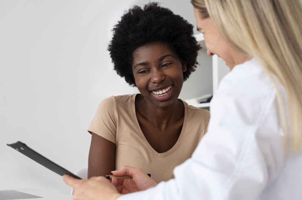 A patient smiles as a doctor talks her through her prescription process